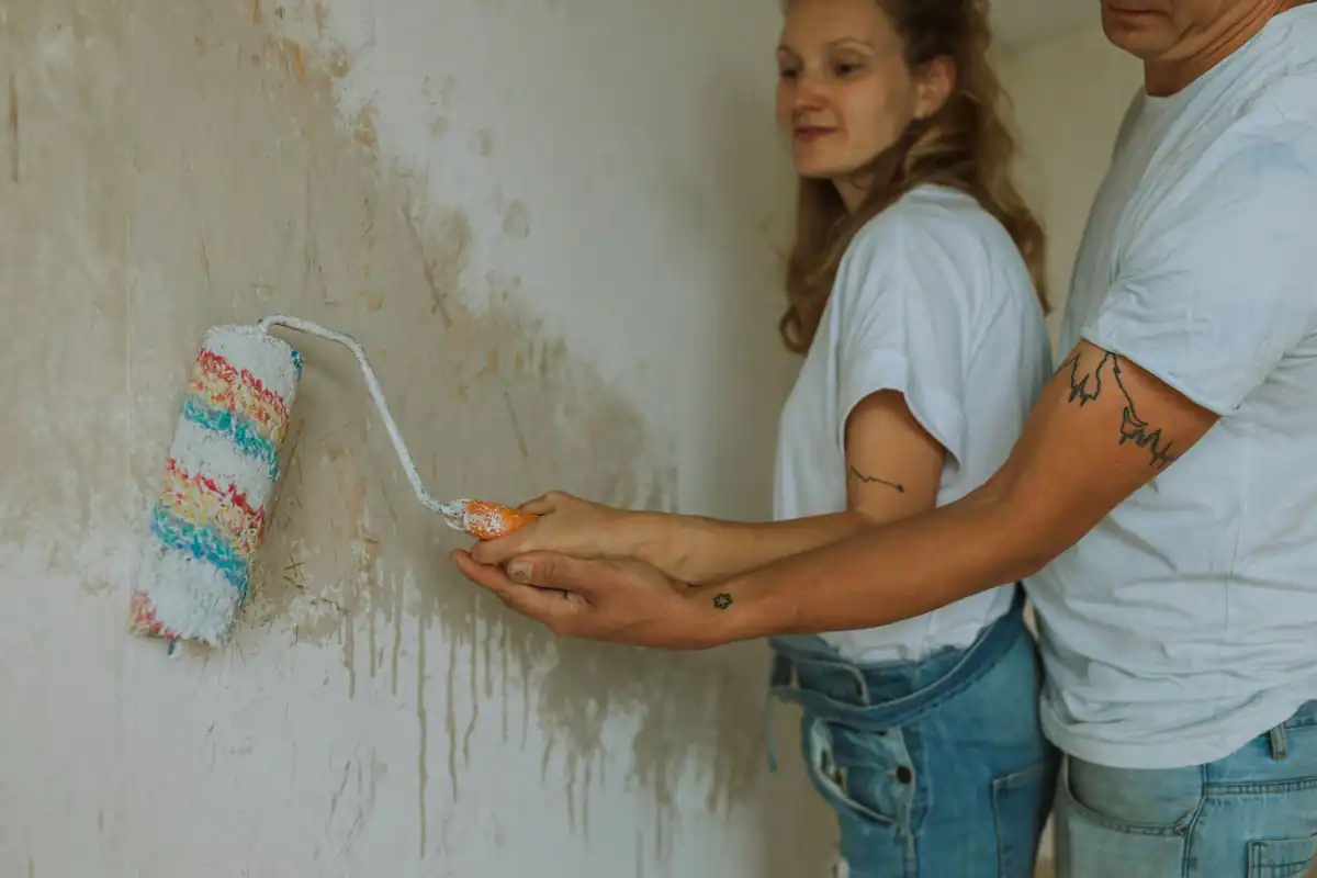 Cuplu care vopsește împreună un perete în timpul renovării