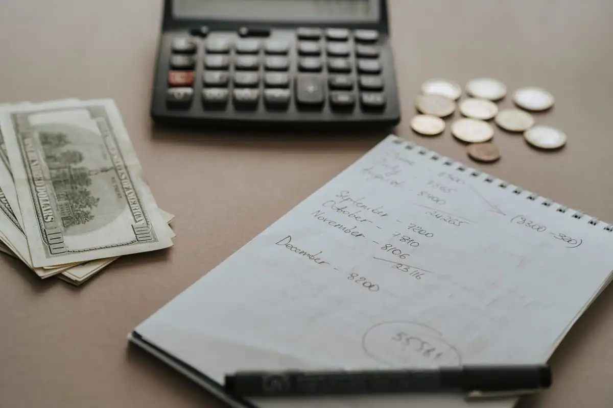 Calculator, bani și notițe pe birou, pentru estimarea bugetului de renovare