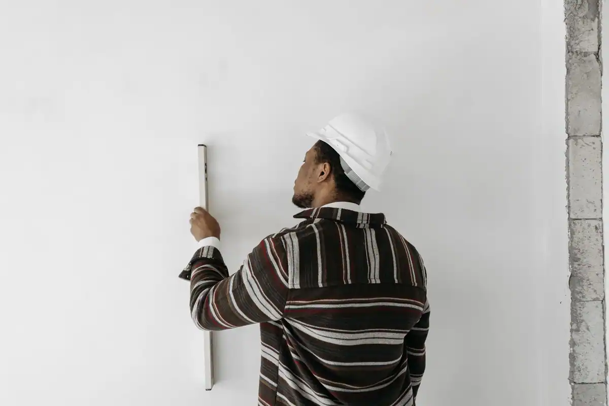 Bărbat care verifică verticalitatea peretelui cu o nivelă