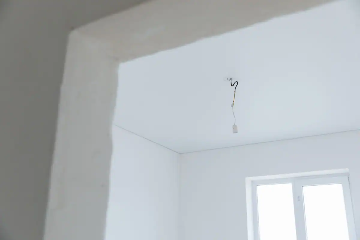Cameră albă în renovare, cu cablajul electric la vedere înainte de gletuire