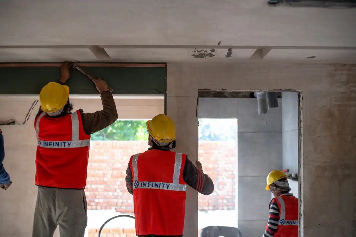 Muncitori cu echipament de protecție care renovează un spațiu interior