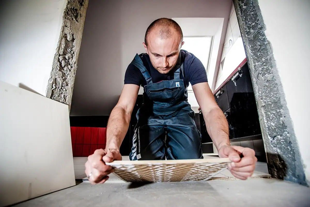Muncitor care montează plăci ceramice de teracotă și le verifică cu nivela
