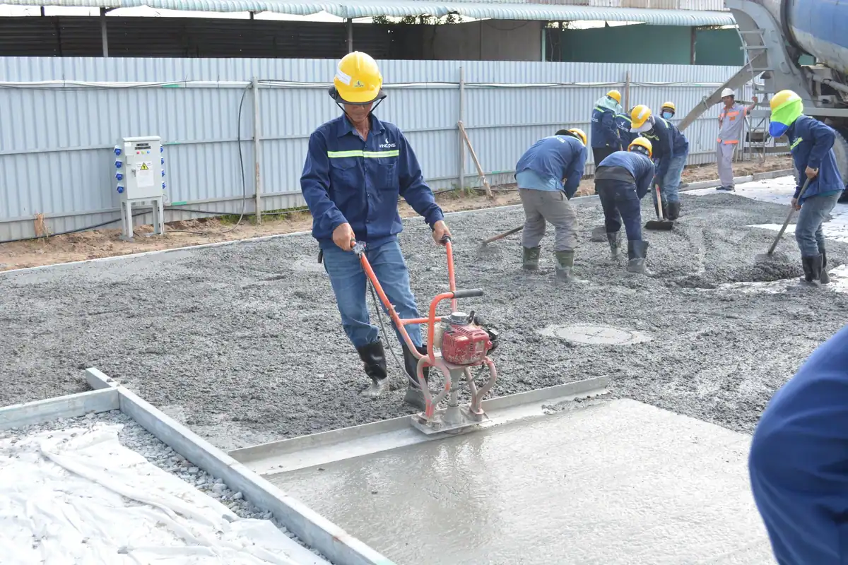 Muncitori care nivelează betonul proaspăt turnat
