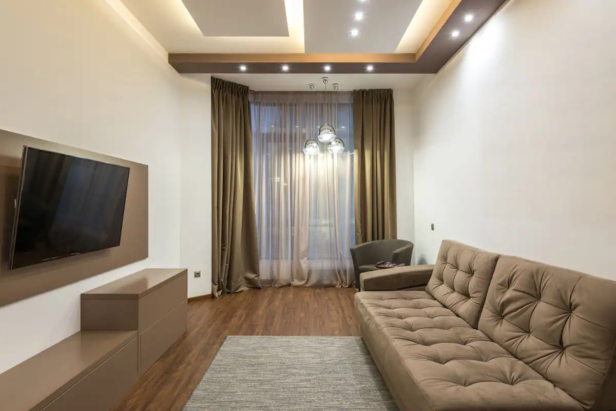 Living bej cu televizor, canapea și iluminat integrat în tavan