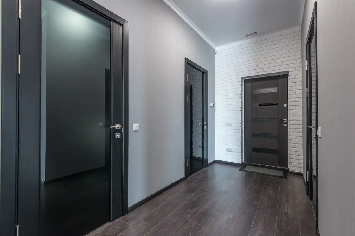 Hol spațios cu parchet laminat și uși negre cu geam
