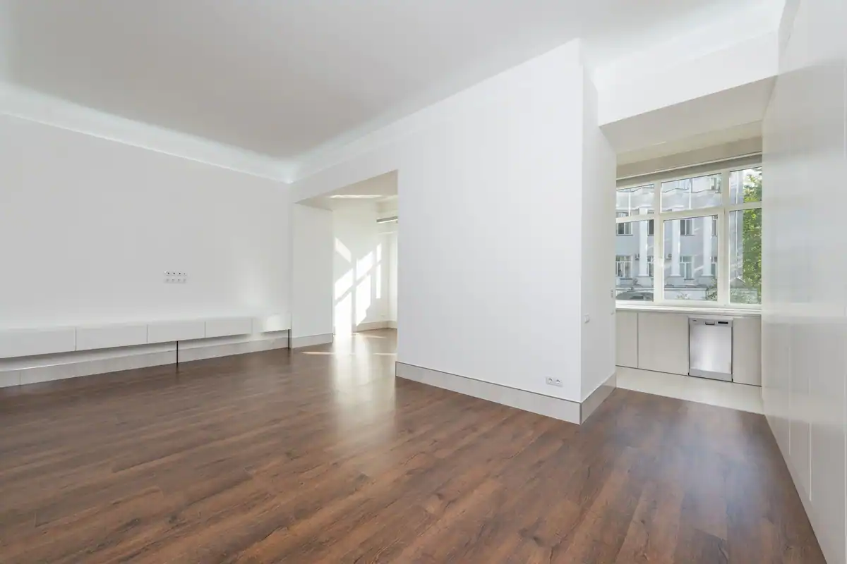 Apartament gol cu pereți albi, parchet și ferestre mari